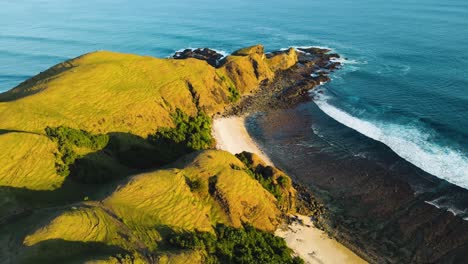 tomado en órbita aérea sobre la isla de lombok con las famosas colinas de bukit merese y playas de arena con olas que se estrellan desde el océano. lombok, indonesia.