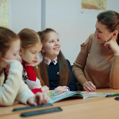 group of schoolgirls with a teacher. young teacher having a conversation with school children in the classroom. students of elementary school during the lesson.