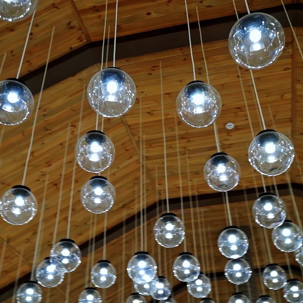 Crystal balls hanging from brown ceiling. Beautiful ceiling with round glass light bulbs. Motion camera around.