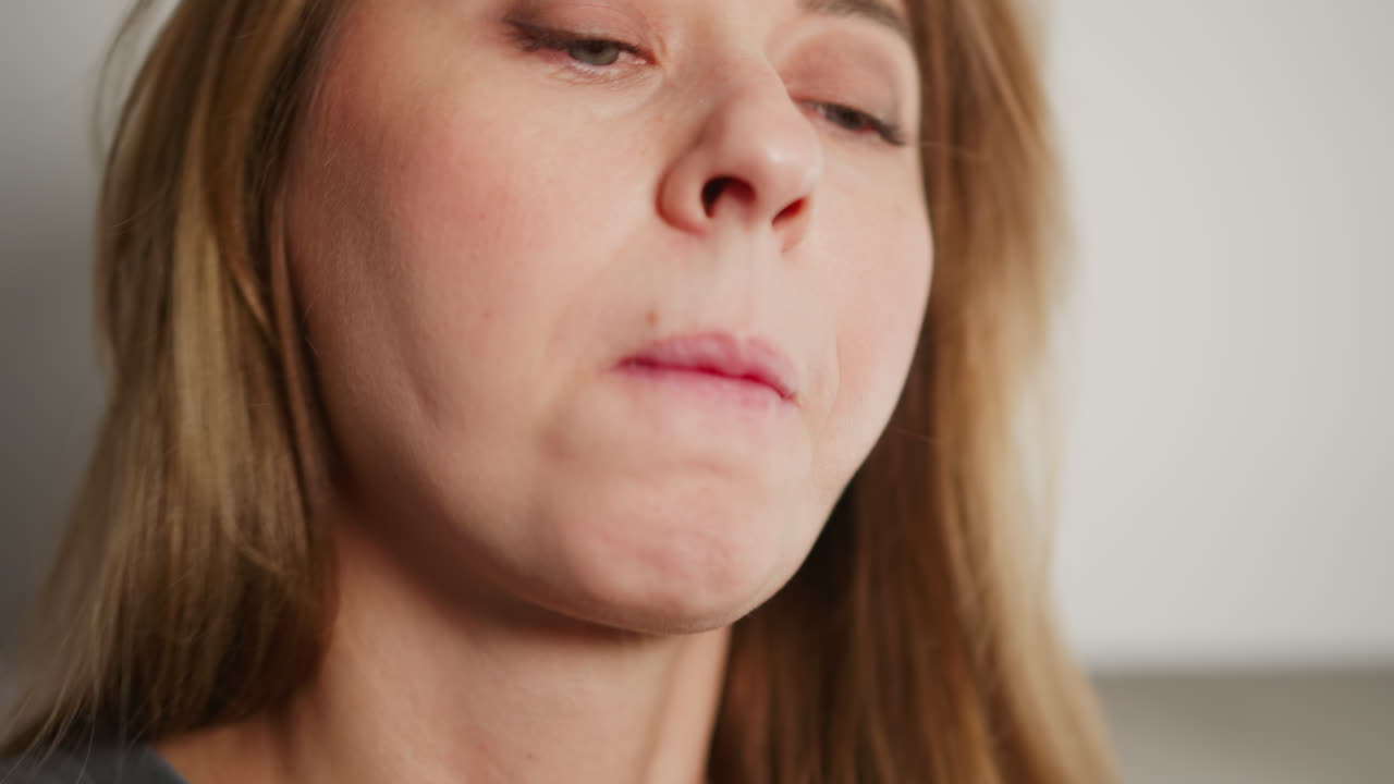 Extreme close up of young woman adjusting hair while using chopsticks to eat pasta, capturing delicate moment with soft natural lighting highlighting facial features