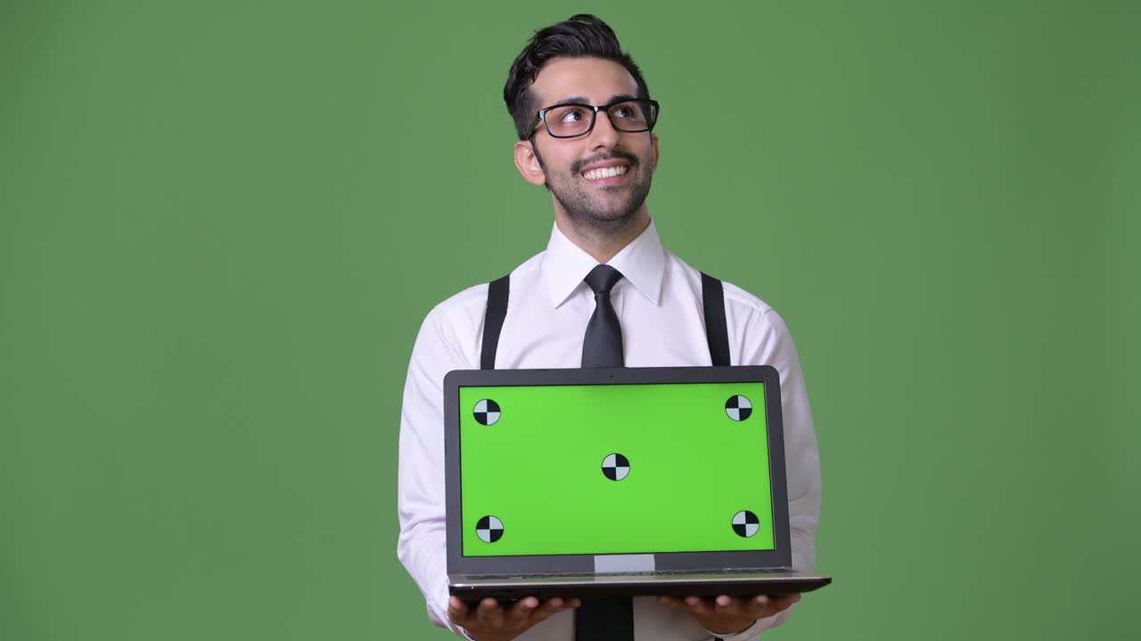 joven empresario persa barbudo y guapo contra un fondo verde