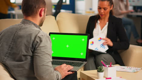 Back-view-of-business-man-sitting-on-couch-using-laptop-with-green-screen