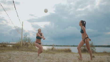 Olympische-Sport-Beachvolleyball-Frauen-Trainieren-Im-Sommer-Auf-Offenem-Platz-Am-Ufer-Des-Flusses,-Sportliche-Und-Aktive-Damen