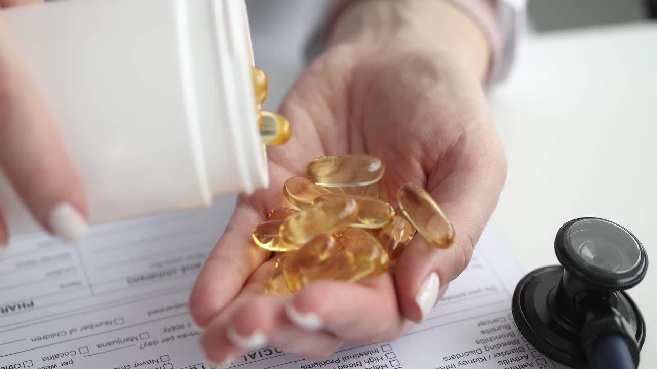 Mano di donna che versa capsule gialle di omega-3 e olio di pesce.