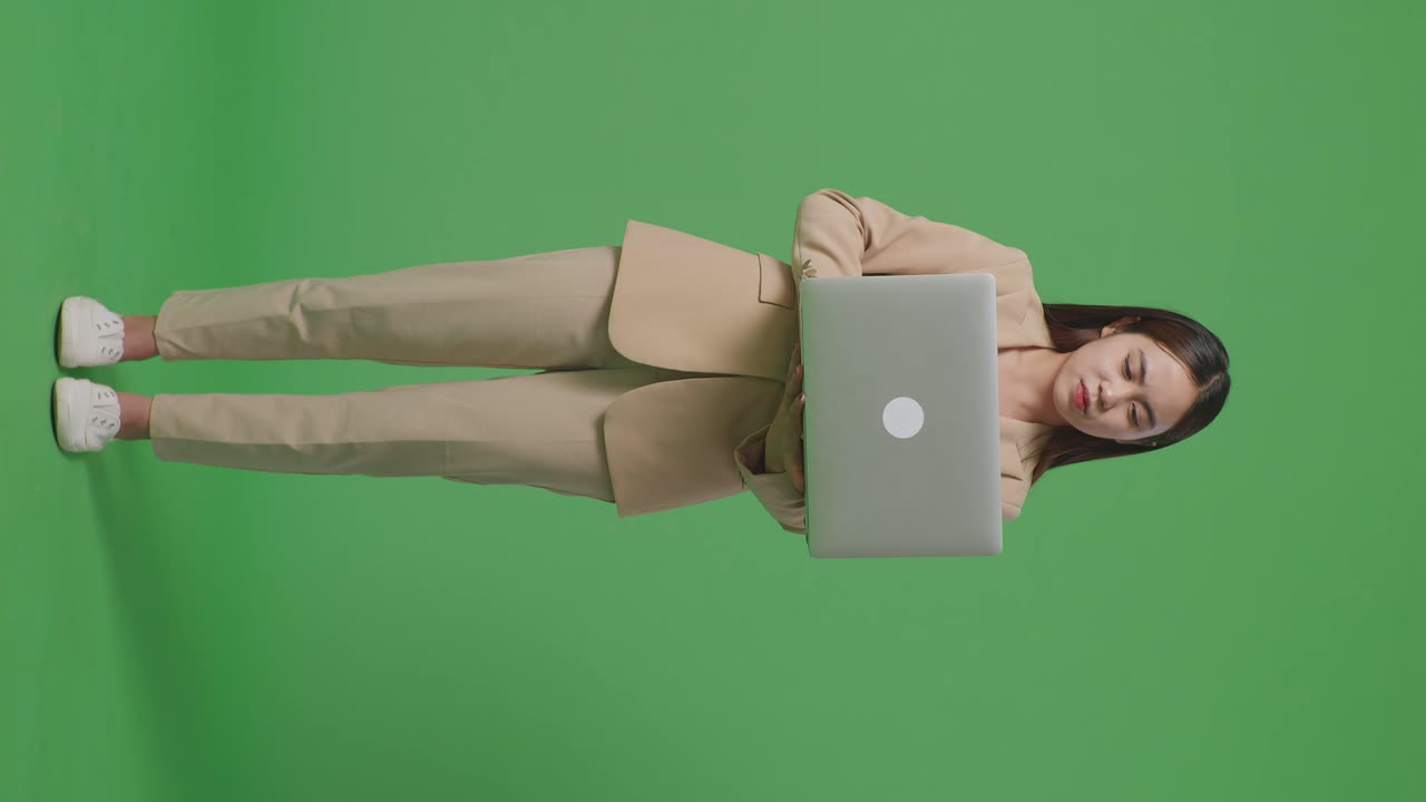 cuerpo lleno de mujer de negocios asiática no está satisfecha y sacude la cabeza mientras usa la computadora portátil en el estudio de pantalla verde
