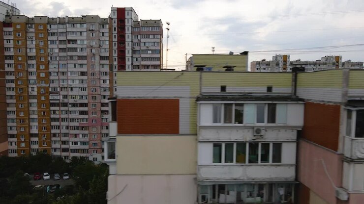 Vista aérea em frente a janelas quebradas e apartamentos queimados e com fuligem, em um prédio antigo, em um bairro pobre de Kiev, dia nublado, na Ucrânia - tomada de drone com rastreamento.