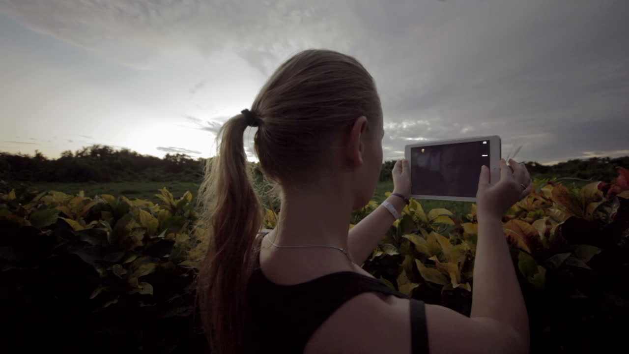 자연 장면의 사진을 찍기 위해 태블릿 pc를 사용하는 여성