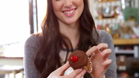 mujer sonriente sosteniendo un cupcake