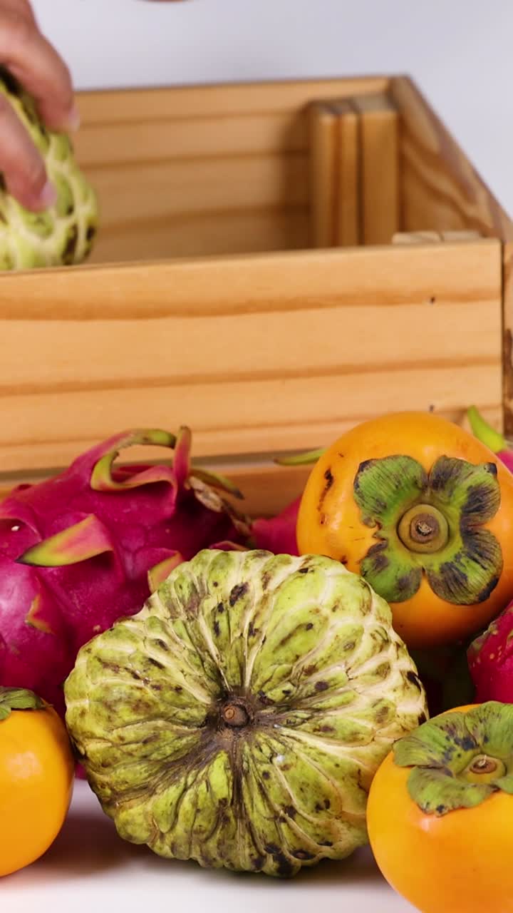 manos colocando varias frutas en una caja