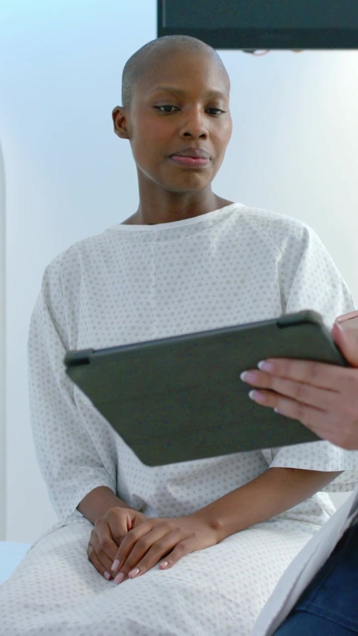 Vertical video: Turning woman in gown toward tablet arriving from right in clinic, checking results