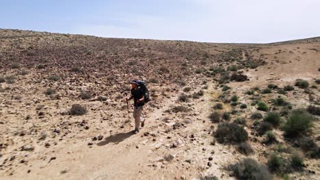 il drone veloce vola verso l'escursionista che percorre una pista nel paesaggio roccioso del deserto