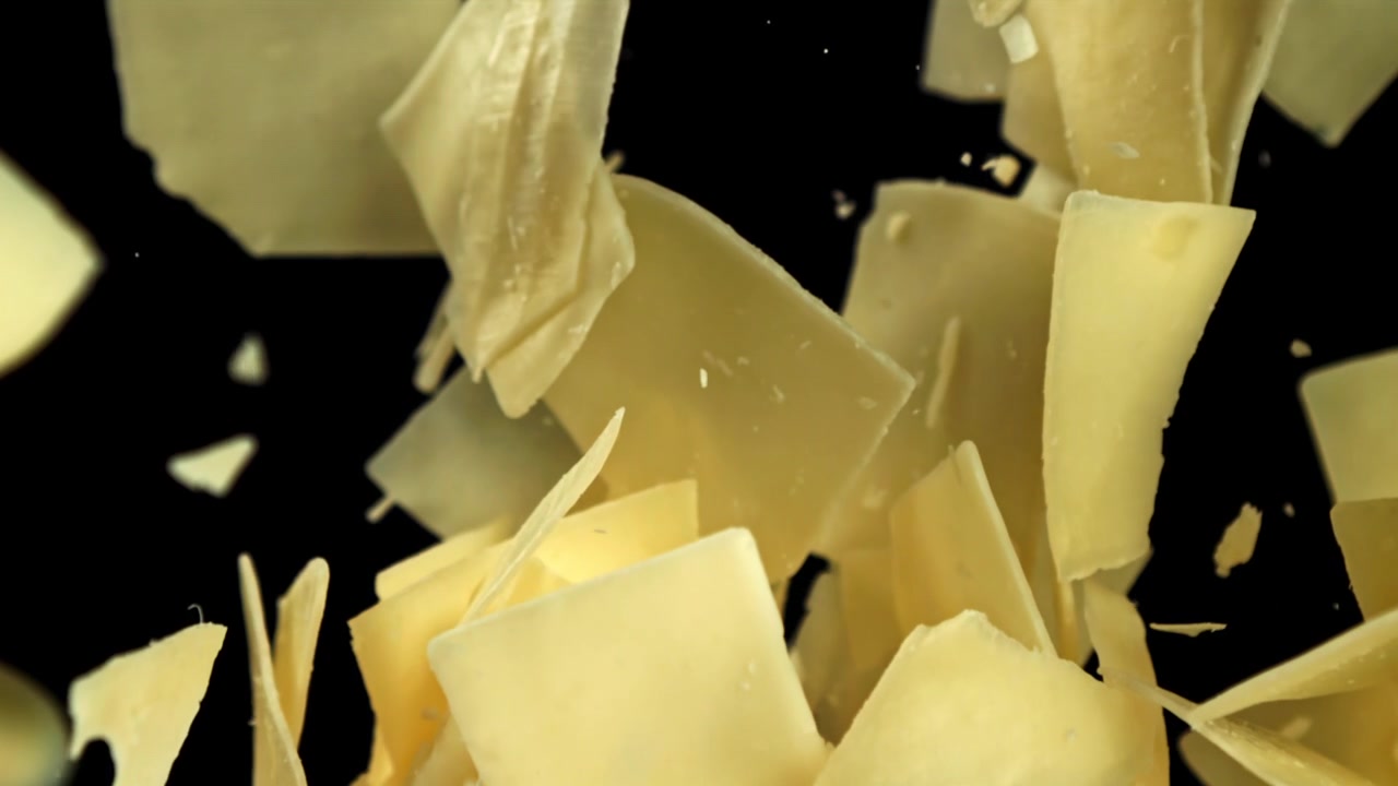 Slow Motion Falling Parmesan Cheese Shavings on Black Background