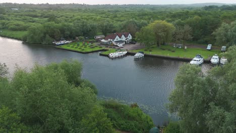 an aerial shot above the river yare, with boats moored near the shore and lush green forests stretching to the horizon