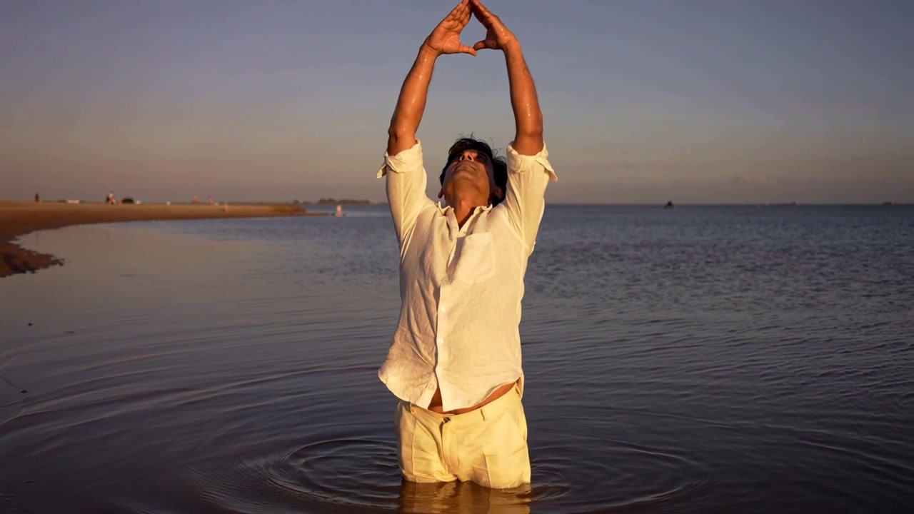 Starting with arms at chest height, South Asian man lifting hands into diamond, wearing white shirt