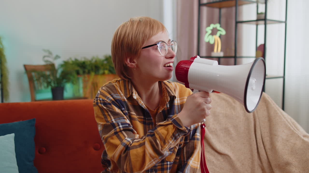 Young woman talking with megaphone proclaiming news loudly announcing advertisement at home room