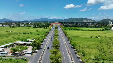 Aerial-view-of-Tembolak-Gateway-on-the-highway-in-sunny-sky-and-mountain-range-on-the-background