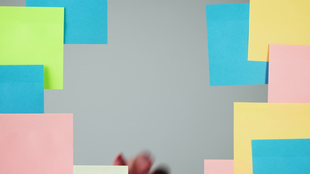 Mano che posiziona post-it colorati vuoti su sfondo grigio