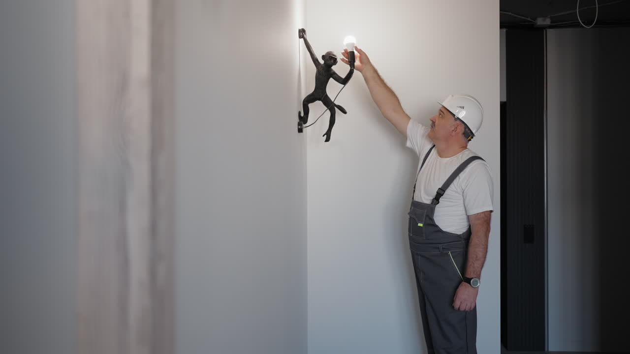 The electrician inserts a light bulb and checks the operation of the light bulb in the lamp for the children's room.