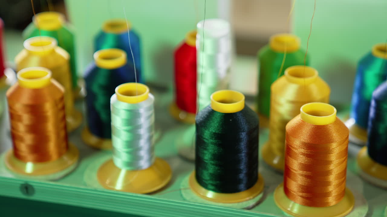 Bright threads in spools for tailor. Colorful spools with threads for sewing industry. Different colors of threads on the table. Handicraft.