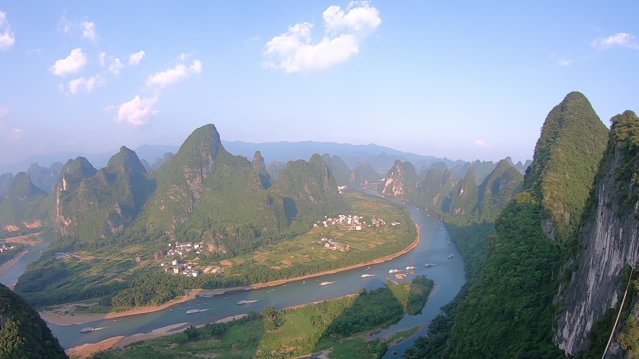 Time-lapse clip of tourists ships sailing on the Li River as seen from the Xianggong Hill viewpoint over lush and dense karst mountain landscape in Yangshuo, Guangxi Province, China