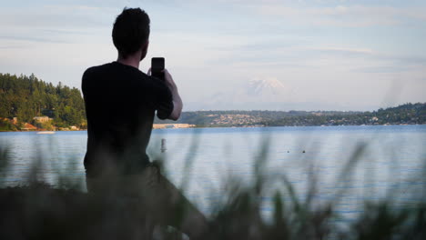 Static shot of young man taking pictures and selfies with a cell phone in front of Mt
