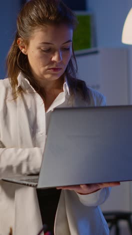 vertical video: focused businesswoman checking company reports standing in start up office