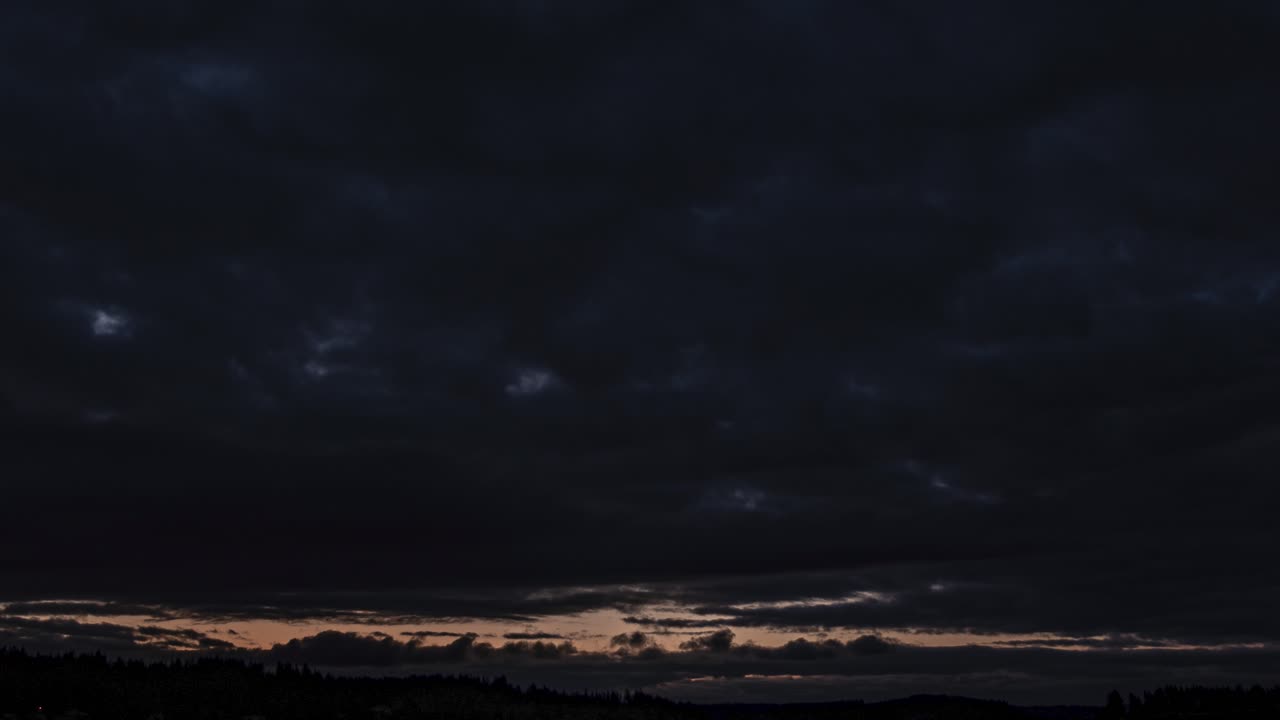 Rushing hyperlapse post apocalyptic storm clouds over a distant body of dark water at sunrise, Pan left dolly out