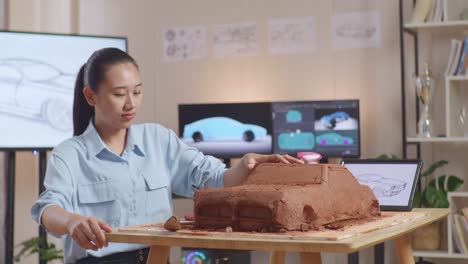 woman carving a clay model car