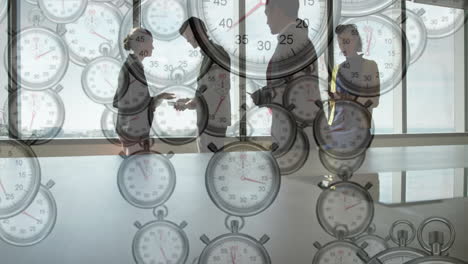 animation of moving clocks over diverse colleagues discussing work in office