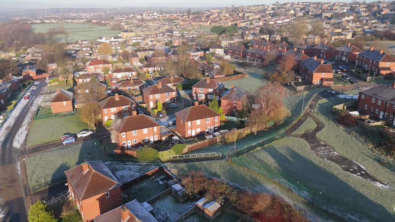 Vista invernale dal drone che riprende un tipico complesso residenziale urbano di proprietà comunale del Regno Unito, il Dewsbury Moore Council estate, con case a schiera in mattoni rossi e la zona industriale dello Yorkshire.