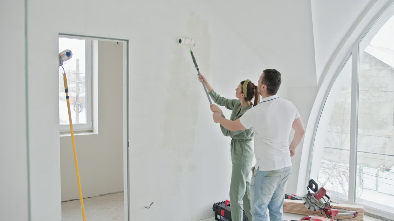 pareja pintando una pared en un nuevo hogar