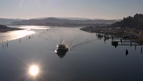 aerial dolly shot over backlit tugboat and shoreline on oregon’s coos bay