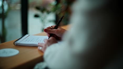 woman taking notes in a cafe