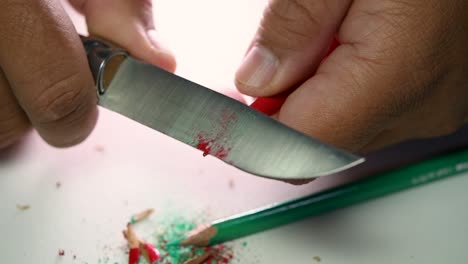 imágenes de manos afilando lentamente un lápiz y algunos lápices de colores con un cuchillo afilado