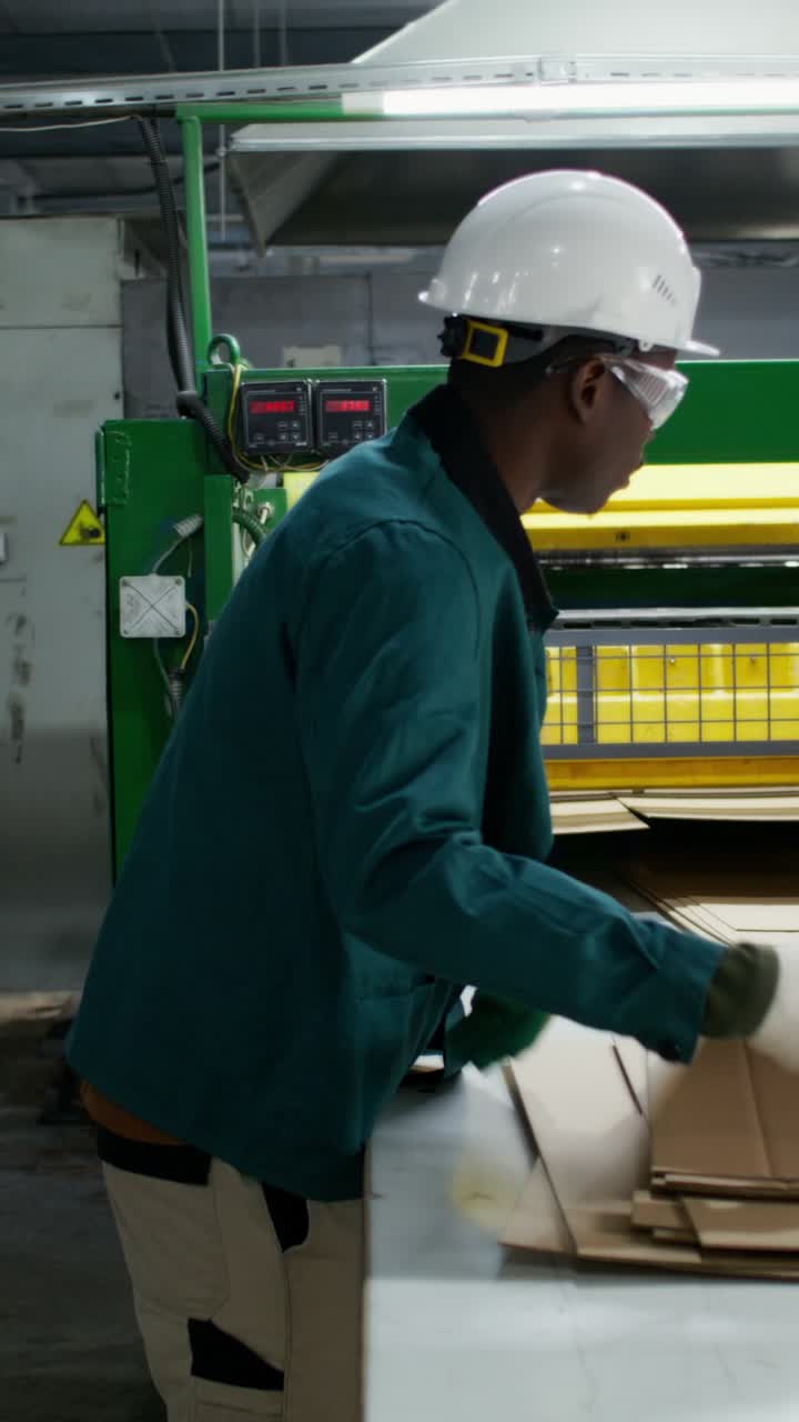 Worker in a recycling plant sorting and processing cardboard