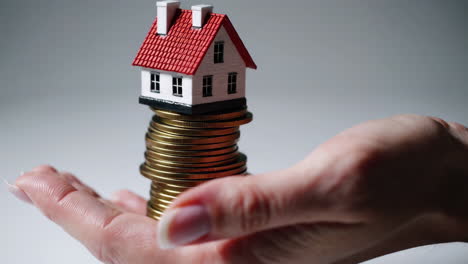 house on a stack of coins in hand