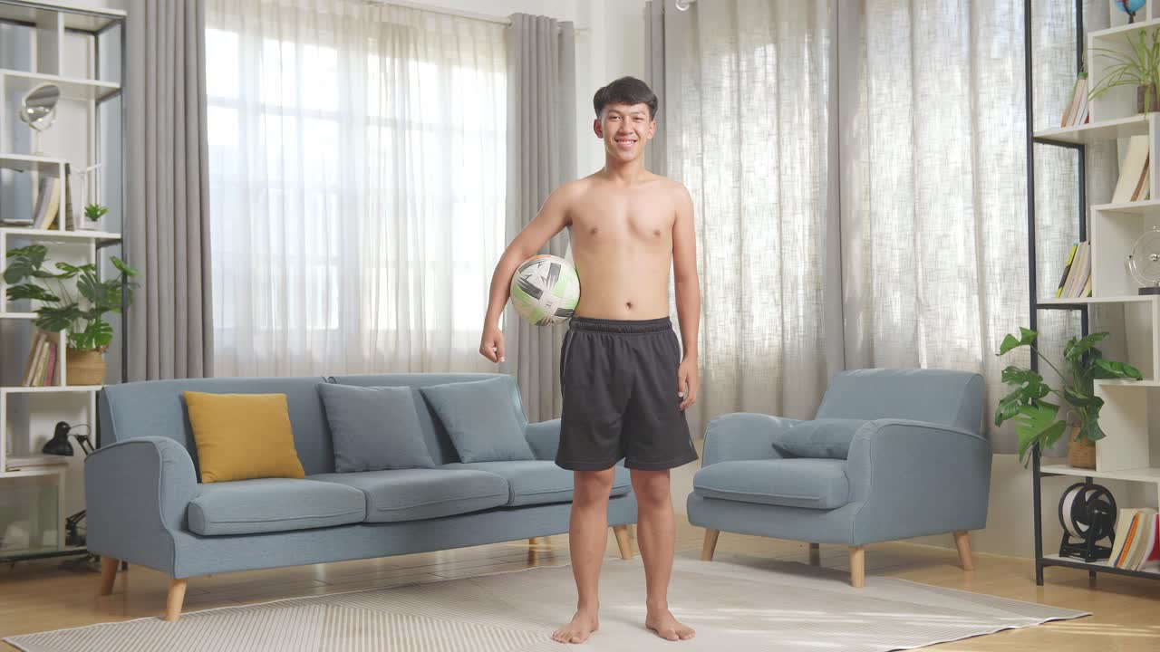 십대 가 거실 에서 축구 공 을 들고 있다