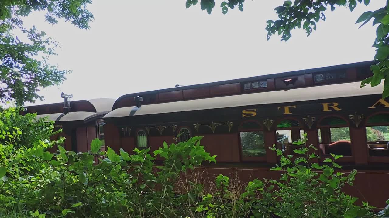A Steam Train Passes Bye in the Countryside With Scenic Views of Fields and Distant Mountains