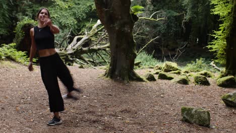 Frontal-view-of-athletic-young-woman-rehearsing-ginga,-forest-meadow