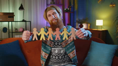 hippie man showing multiracial different skin color human shape cut out of paper against racism