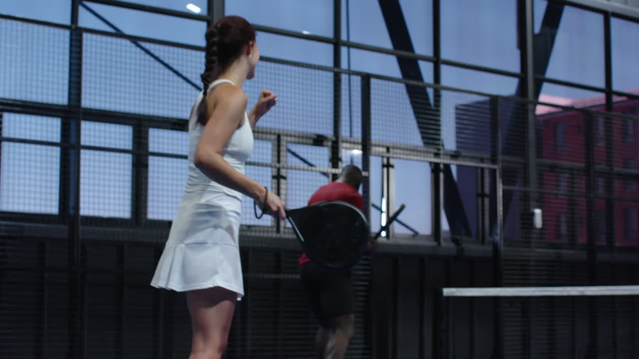 Diverse players enjoying intense padel tennis match on indoor court, focused and determined