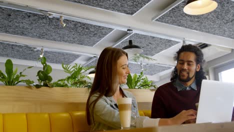 couple discussing over laptop in cafeteria 4k