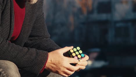 A-stylishly-dressed-man-puts-together-a-rubik's-cube-puzzle