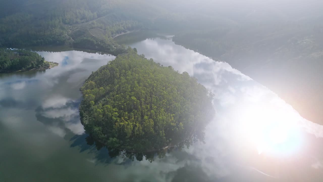 Drone view of Meandro El Melero natural river bend surrounded by forest and mountains with morning mist and water reflections in Extremadura Spain. Scenic travel landscape in golden light