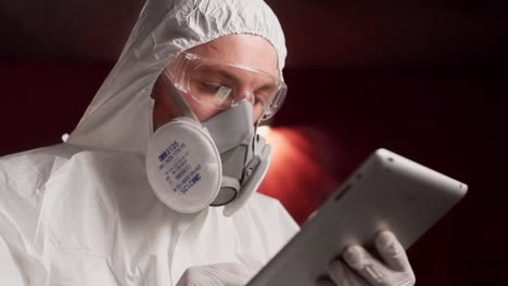 man in protective mask and glasses flips news on tablet