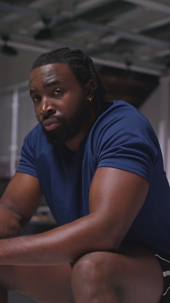 Vertical Video Portrait Of Determined Male Athlete Sport Training In Gym Sitting And Concentrating In Changing Room With Focused Expression