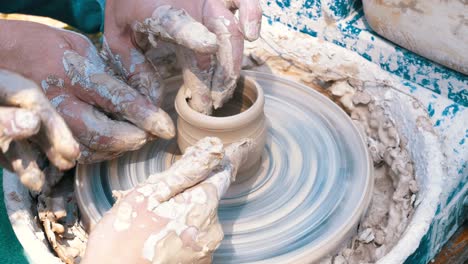 potter's hands work with clay on a potter's wheel