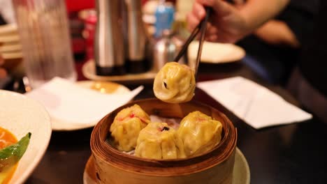 person picking dumplings from a steamer basket