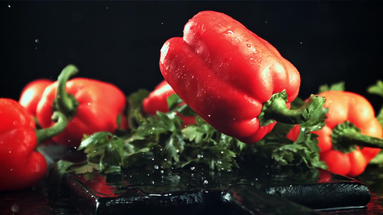 Čerstvá červená paprika padající ve zpomaleném záběru s cákanci vody