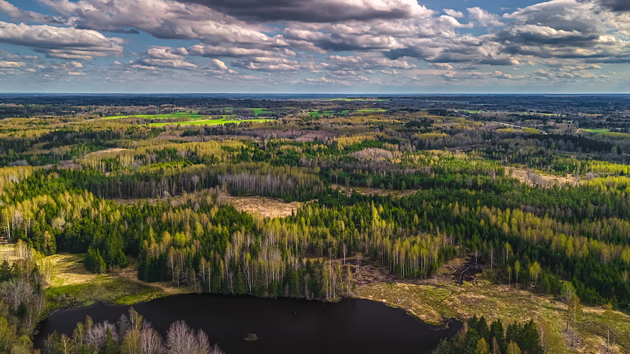 Meadows, fields, forests, and pond in a rural, European landscape under a dreamy cloudscape time lapse as shadows pass over the Earth